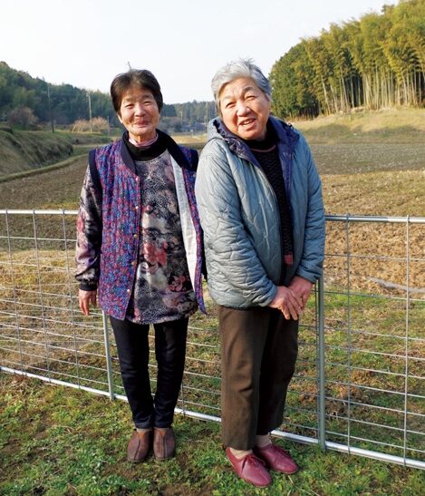 今橋常子さん（左）と矢田菊枝さん。後ろの圃場は今橋さんが草刈りを担当するエリア